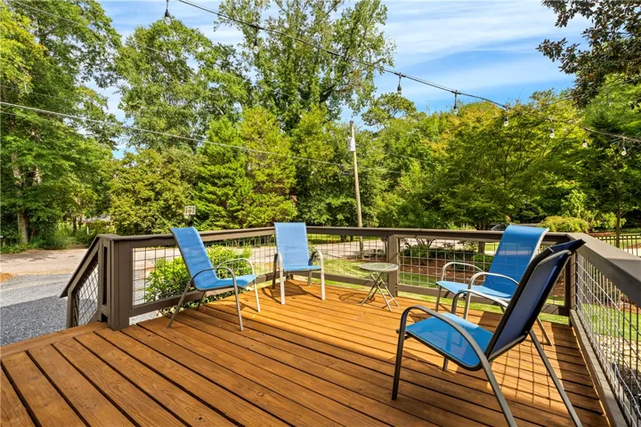 An elevated wood deck overlooks a lush yard bordered by mature trees.