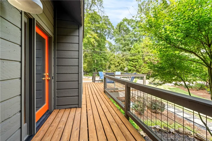 A spacious wooden deck overlooks a lush, tree-lined yard.