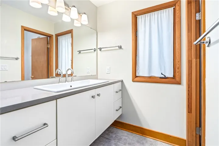 Natural wood casing accents a wood-framed window alongside a clean vanity with modern hardware.