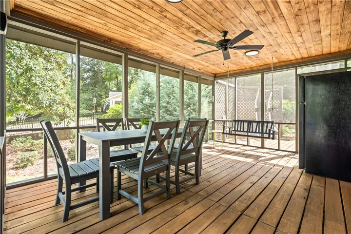 A spacious screened porch features handsome wood plank floors and a matching paneled ceiling.