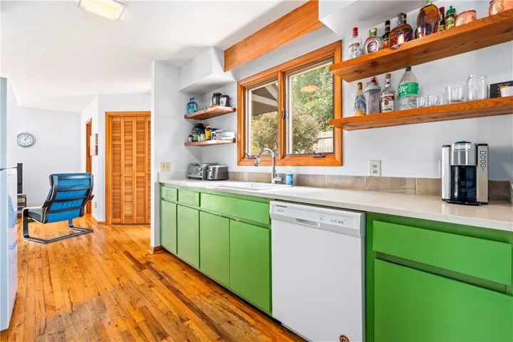 Rich hardwood flooring anchors this kitchen featuring open wood shelving and a functional layout.