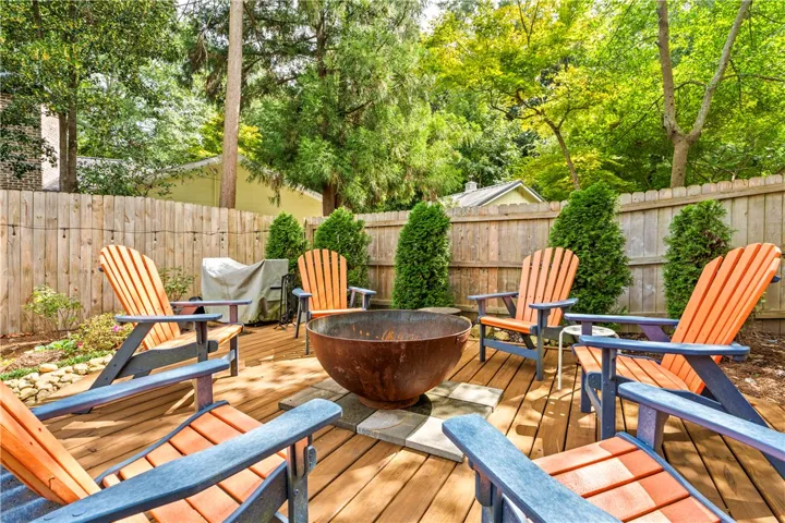 Mature trees frame a private wooden deck complete with a central stone-lined fire pit.