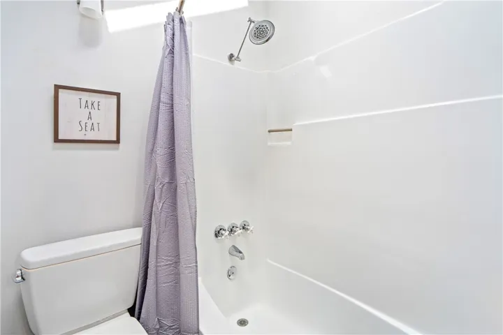 A clean bathtub and shower combination sits adjacent to the toilet in this functional space.