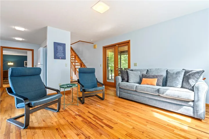 Warm hardwood flooring runs throughout this inviting living space next to a wooden staircase.