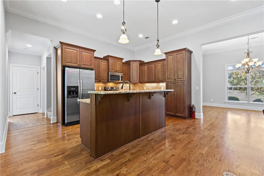 Gleaming hardwood floors anchor this open-concept kitchen with extensive wood cabinetry and stone countertops.