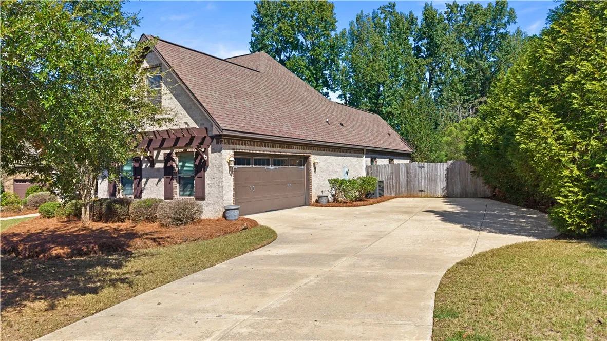 An expansive concrete driveway leads to the side-entry garage framed by classic brick architecture.