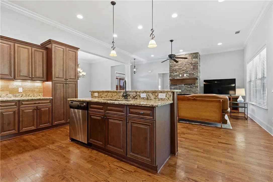 Rich wood cabinetry and stone counters anchor this bright, open kitchen overlooking the living space.