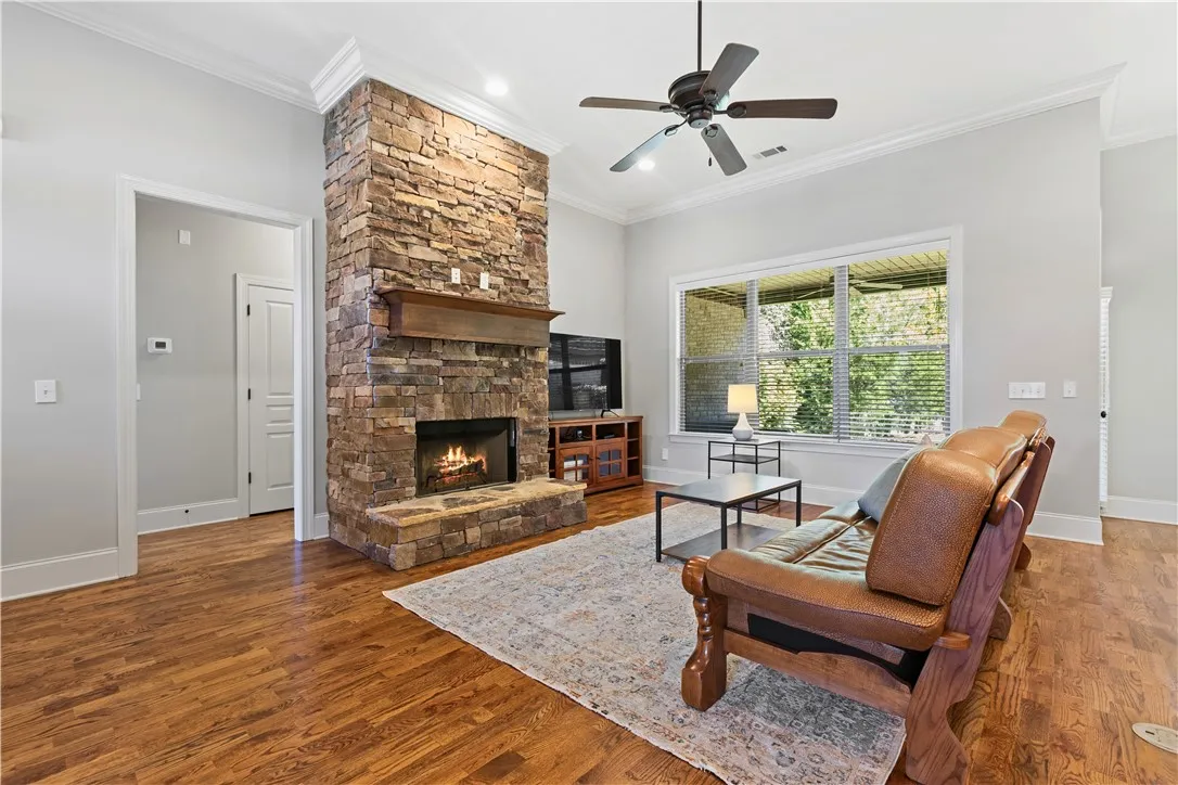 Rich hardwood floors and a floor-to-ceiling stone fireplace define this inviting living space.