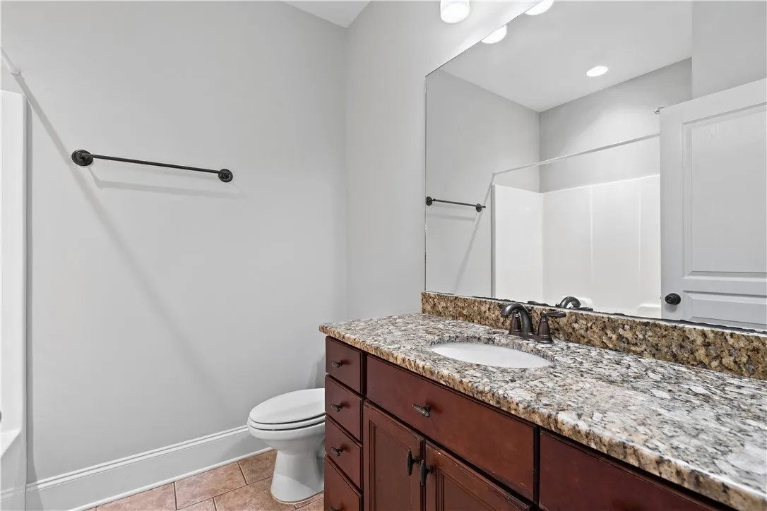Rich wood cabinetry is paired with stone countertops and tile flooring.