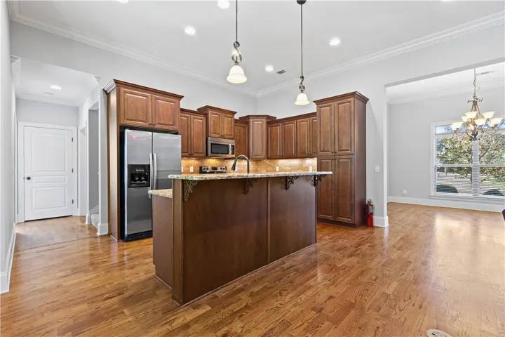 Gleaming hardwood floors anchor this open-concept kitchen with extensive wood cabinetry and stone countertops.