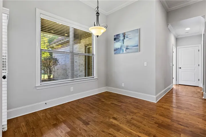 Rich hardwood floors and classic crown molding elevate this versatile dining or breakfast area.