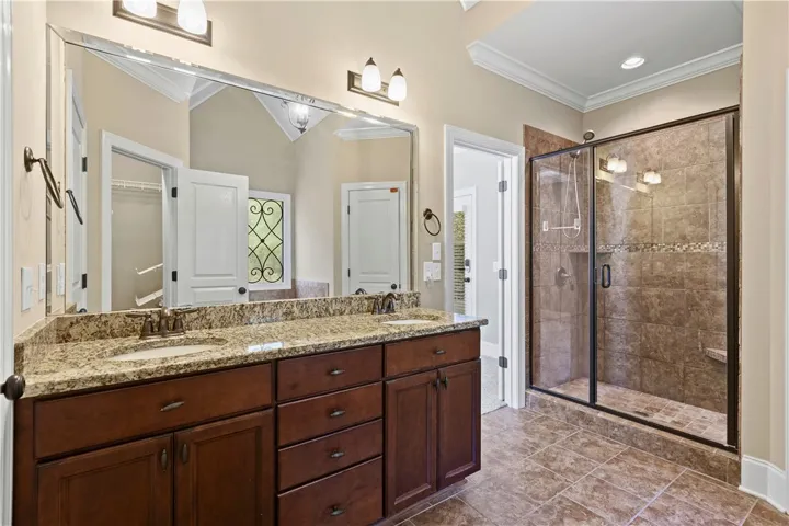 A spacious double vanity and a glass-enclosed walk-in shower define this elegant bathroom.