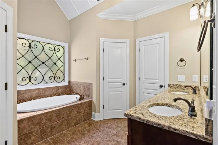 A vaulted ceiling and decorative window frame this bathroom featuring a deep soaking tub.
