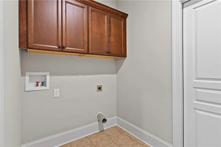 A functional laundry area includes overhead storage cabinets and durable tile flooring.