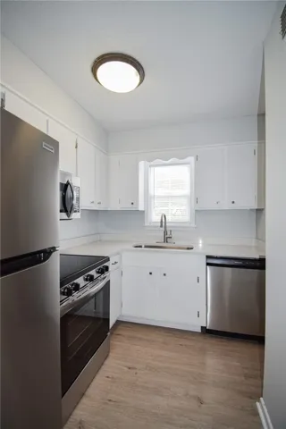 Streamlined cabinetry and modern stainless appliances define this efficient culinary space with wood-style flooring.