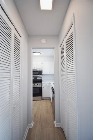 Louvered closet doors flank a hallway leading directly into the kitchen.