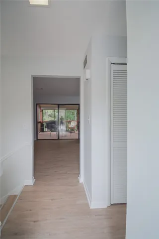 Smooth wood floors and neutral walls connect the upper hallway to a bright living area.