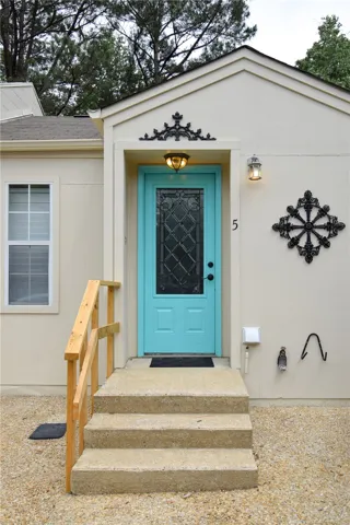 Concrete steps lead to a welcoming entry with decorative ironwork details.