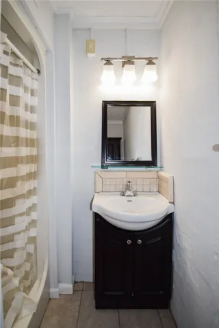 Tiled flooring and a modern dark wood vanity maximize space in this efficient bathroom.