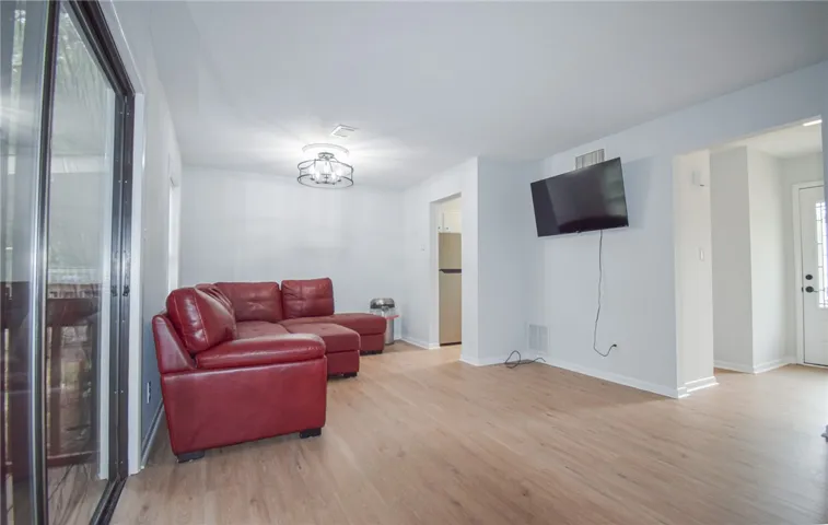 Warm wood flooring and sliding glass doors define this open living area.