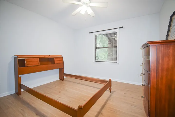 Smooth wood floors anchor this comfortable bedroom complete with a wide central window.