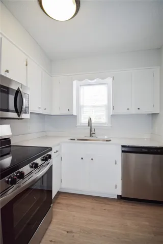 Gleaming wood-look floors pair beautifully with crisp white cabinetry and a central window.