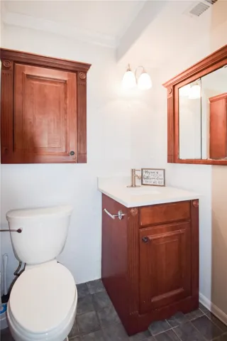 Rich wood cabinetry paired with dark stone tile floors defines this elegant powder room.