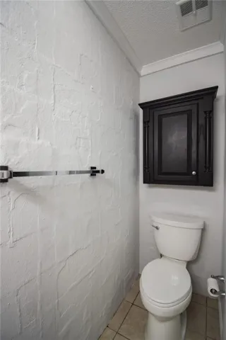 Textured walls and crown molding frame this functional half bath space.