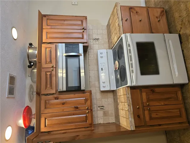 Warm wood cabinetry pairs with tiled countertops and recessed lighting in this functional kitchen space.