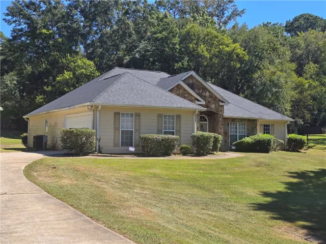 Mature trees frame a classic stone and siding exterior fronted by a manicured lawn.