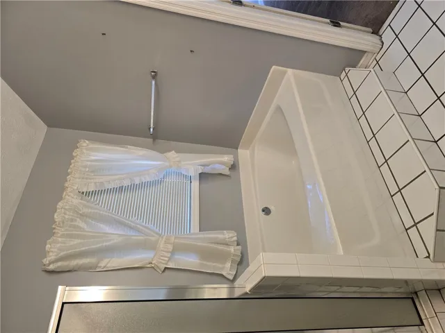 A classic soaking tub is bordered by neat tiling under a bright window.