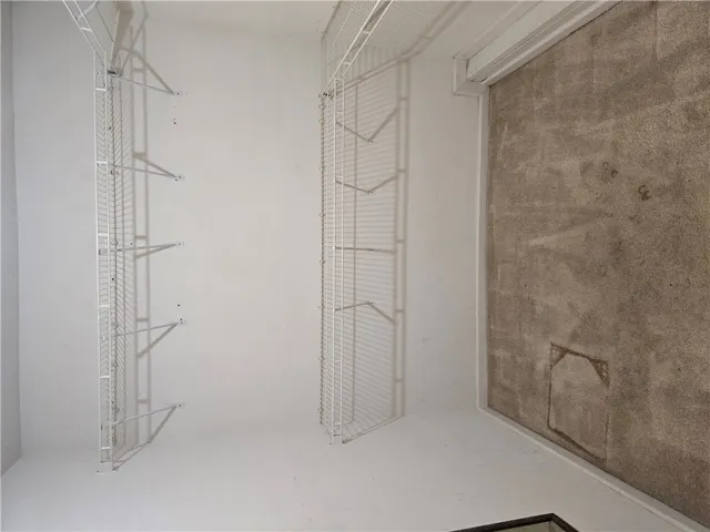 Ample wire shelving lines this functional closet space situated off a carpeted room.
