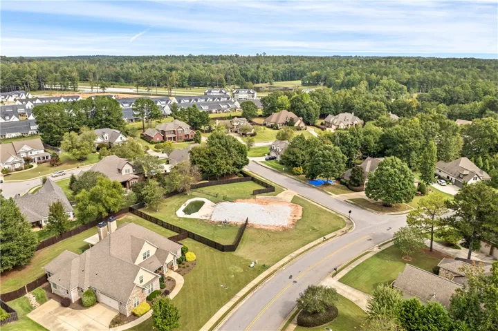 An aerial perspective showcases a peaceful residential neighborhood bordered by dense green woodlands.