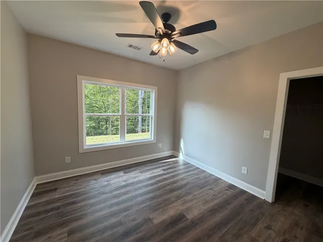 Gleaming wood floors anchor this comfortable bedroom overlooking peaceful backyard trees.