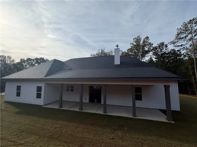 A spacious covered back porch offers quiet outdoor living overlooking the grassy yard.