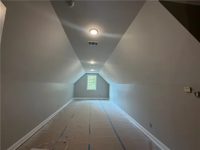 Sloped ceilings frame this unfinished bonus room punctuated by a single end-wall window.
