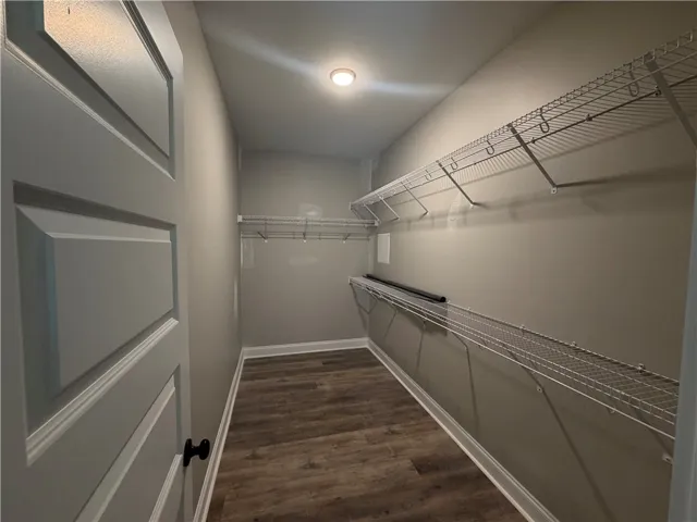 Ample wire shelving lines this functional walk-in closet featuring durable vinyl plank flooring.