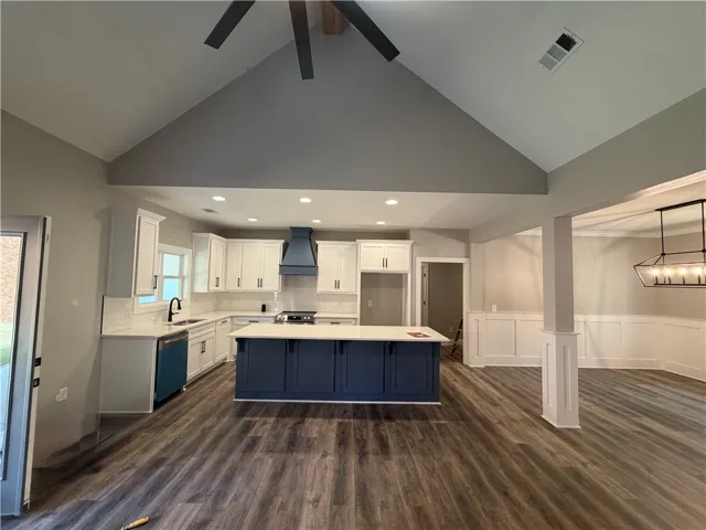 High vaulted ceilings and rich wood-look flooring anchor this airy, open-concept kitchen space.