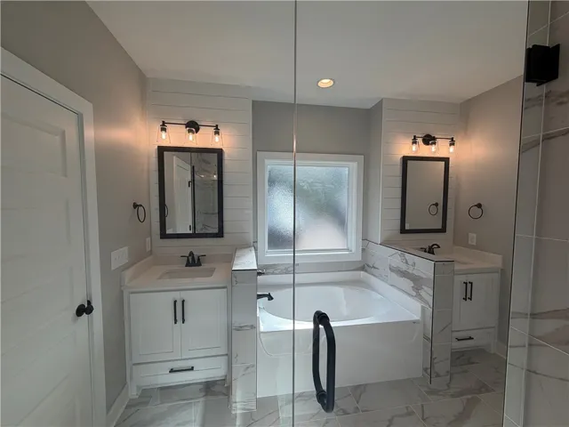 Polished tile flooring and a central soaking tub anchor this refined bathroom space.