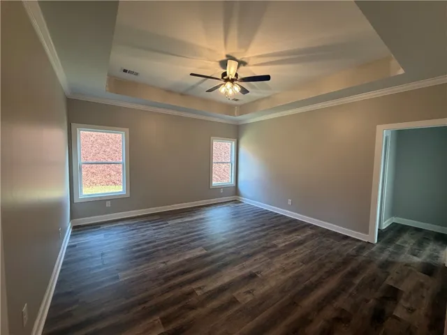 Gleaming hardwood floors and a deep tray ceiling elevate this versatile bedroom space.