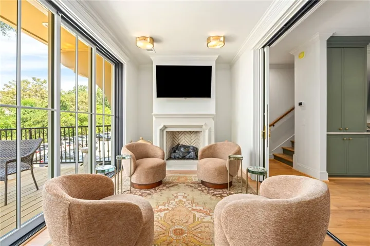 Floor-to-ceiling glass doors open to a private balcony from this bright fireplace-centered sitting room.