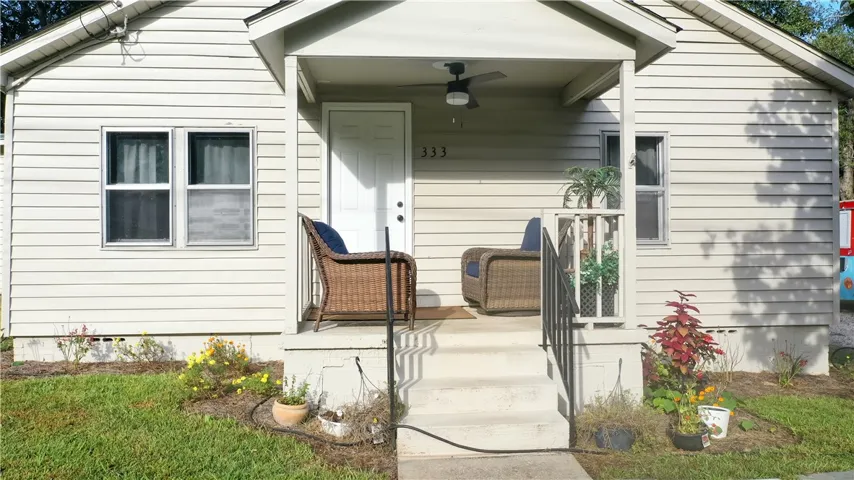 Concrete steps ascend to a welcoming covered front porch framed by classic siding.