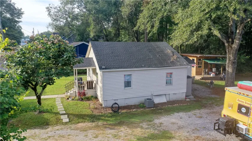 Mature trees frame a classic single-story home with a gabled shingle roof and vinyl siding.