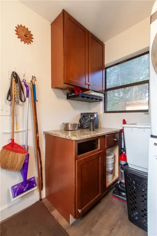 A functional utility space with wooden cabinets and granite countertops provides excellent storage potential.