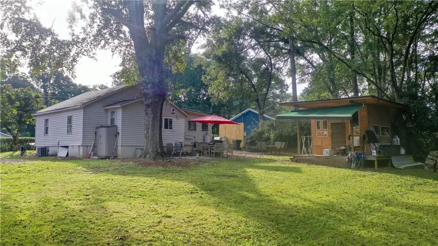 Mature trees shade a spacious lawn surrounding this residential property and its detached outbuildings.