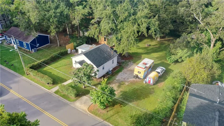 Mature trees surround this property, highlighting a spacious grassy yard and private setting.