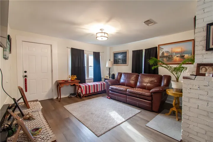 Rich wood-look flooring and a brick fireplace column anchor this inviting living space.