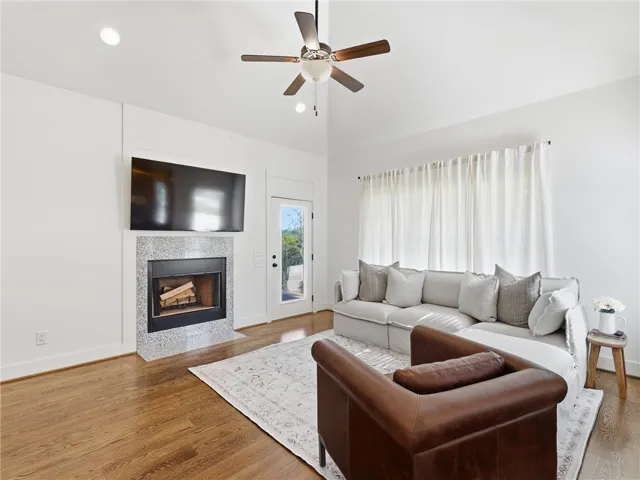 Rich hardwood floors and a modern fireplace anchor this bright, high-ceilinged living space.