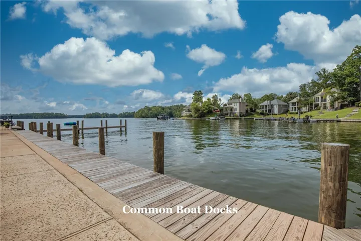 Wooden docks stretch across quiet waters beneath a bright blue sky filled with clouds.