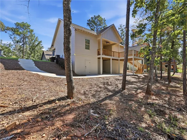 Mature trees frame the walkout basement and elevated wooden deck of this contemporary siding home.